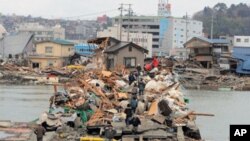 Residents cross a bridge covered with debris after the March 11 earthquake and tsunami in the city of Ishinomaki in Miyagi prefecture on March 15, 2011