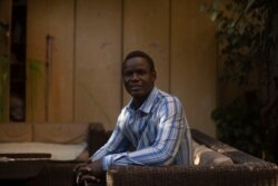 Patrice Gaudensio, a refugee artist from South Sudan poses for a portrait during an exhibition featuring work by refugee artists, at Art Cafe in Cairo, Nov. 27, 2019. He said he and his wife experienced racism, discrimination several times in Cairo.