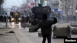 Seorang demonstran melemparkan batu kepada polisi saat bentrokan di Pristina, Kosovo, 9 Januari 2016. 