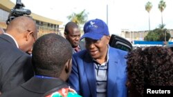 Uhuru Kenyatta (C) arrives at the Jomo Kenyatta International Airport as he departs to attend a hearing at the International Criminal Court at The Hague, in Nairobi, October 7, 2014.