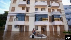 A man rows a makeshift boat through an inundated street flooded by heavy rains, in Porto Alegre, Brazil, May 7, 2024.