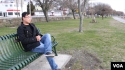 Roger Williams University graduate student Qiming Li sitting near the water in Bristol.