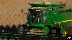 FILE - A farmer uses a combine to harvest his soybean field Oct. 21, 2014, in Loami, Ill.