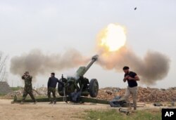 FILE - Iraqi security forces fire at Islamic State positions from villages south of Mosul, Iraq, March 26, 2016.