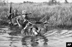 FILE - In this March 11, 1972 file photo, a South Vietnamese soldier holds his personal belongings in a plastic bag between his teeth as his unit crosses a muddy Mekong Delta stream in Vietnam near the Cambodian border. His unit was charged with stemming Communist infiltration from Cambodia into South Vietnam in the heavily populated Mekong Delta area. (AP Photo/Nick Ut)