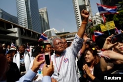 FILE - Protest leader Suthep Thaugsuban greets the crowd as he leads anti-government protesters marching through Bangkok's financial district, Jan. 21, 2014.
