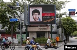 FILE - People ride their motorcycles past a digital billboard showing a sketch of the main suspect in Monday's attack on Erawan shrine, in Bangkok, Thailand, August 23, 2015.