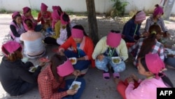 រូបឯកសារ៖ កម្មករ​រោងចក្រ​កាត់​ដេរ​សម្លៀកបំពាក់​កម្ពុជា​កំពុង​ទទួល​ទាន​អាហារ​ពេល​ថ្ងៃ​ត្រង់​នៅ​ក្រោម​ដើម​ឈើ​មួយ​ដើម នៅ​ខាង​មុខ​រោងចក្រ​ដែល​ពួកគេ​ធ្វើការ ភ្នំពេញ ថ្ងៃទី៨ ខែឧសភា ឆ្នាំ២០១៤។ 