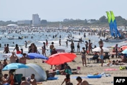 People bathe at a beach during a heat wave in La Grande Motte, southern France, on July 10, 2023. (Photo by Sylvain THOMAS / AFP)