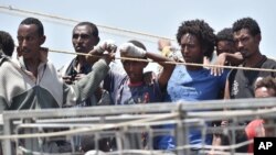 Para migran menanti untuk turun dari kapal angkatan laut Irlandia di pelabuhan Catania, Italia (16/6). 