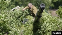 Members of the self-proclaimed Donetsk People's Republic forces walk past an armored personnel carrier (APC) outside the village of Novolaspa in Donetsk region, Ukraine, July 19, 2015. 