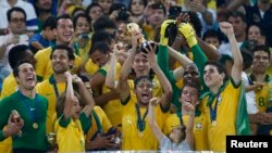 Brazil's Neymar (C) hoists the trophy as he celebrates on the podium with his teammates after winning their Confederations Cup final soccer match against Spain at the Estadio Maracana in Rio de Janeiro Jun. 30, 2013. 