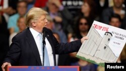 FILE - Donald Trump, then a candidate for the U.S. presidency, holds a sign supporting his plan to build a wall between the United States and Mexico that he borrowed from a member of the audience at his campaign rally in Fayetteville, North Carolina, March 9, 2016.