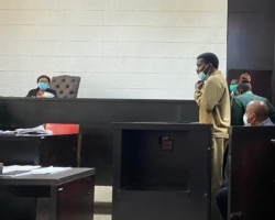 Twenty-eight-year-old Makomborero Haruzivishe (standing) listening to Magistrate Judith Taruvinga (right) reading her ruling on the activist at Harare Magistrates Court on April 06, 2021. (VOA/Columbus Mavhunga)