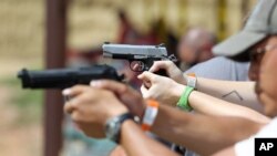 FILE - Shooters practice with pistols at a gun range near Colorado Springs, Colo.