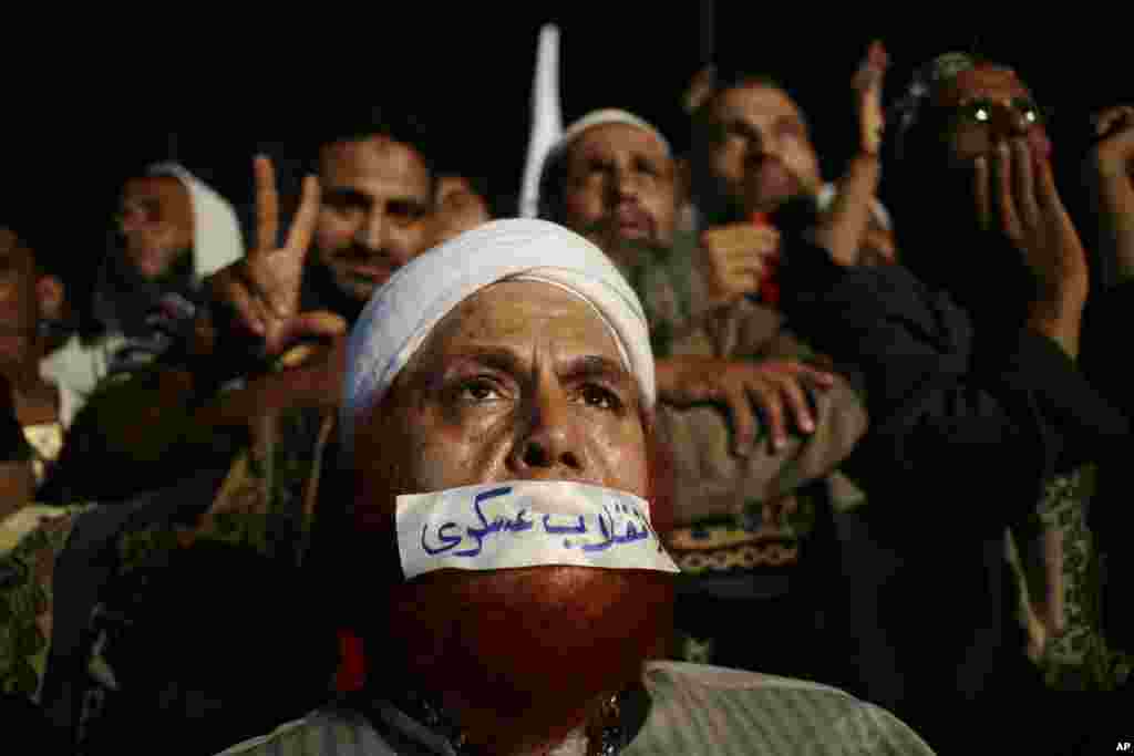 A supporter of Egypt&#39;s ousted President Mohamed Morsi gets relief from the afternoon heat with the help of water sprayers in front of a poster of Morsi, Cairo University,Giza, Egypt.