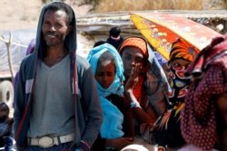 FILE - People wait in line for World Food Program aid, at the Um Raquba refugee camp, which houses Ethiopians fleeing the fighting in the Tigray region, on the border in Sudan, Dec. 3, 2020.