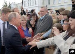 FILE - Russian President Vladimir Putin, left, greets local citizens in Omsk, Russia, Aug. 28, 2018.