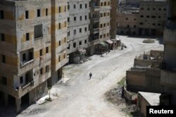 Abu Malek, one of the survivors of a chemical attack in the Ghouta region of Damascus that took place in 2013, uses his crutches to walk along a street in the Ghouta town of Ain Tarma, Syria, April 7, 2017.
