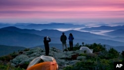 Robert Weiss of Tewksbury, Mass., left, photographs his brother-in-law, Matthew Ferri, of Dracut, Mass., and his wife, Andrea Weiss just before sunrise from their campsite on the Appalachian Trail in Beans Purchase, N.H., Sunday, Sept. 17, 2017. (AP Photo/Robert F. Bukaty)