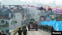 Sebuah kendaraan lapis baja (APC) dan pasukan pemerintah berbaris menuju jembatan Mapandi setelah berlangsungnya pertempuran sengit antara tentara dan pemberontak dari kelompok Maute selama 100 hari, yang telah mengambil alih bagian kota Marawi, Filipina selatan 30 Agustus 2017.