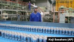 In this Monday, May 29, 2017 photo, Asahi Breweries plant manager Shinichi Uno watches the production line at an Asahi Breweries factory in Moriya near Tokyo. The human job is to make sure the machines do the work right, and to check on the quality