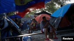 FILE - Venezuelan asylum seekers wait while they attempt to cross into the U.S. by an appointment through the Customs and Border Protection app, called CBP One, at a makeshift camp, in Matamoros, Mexico June 20, 2023. (REUTERS/Daniel Becerril)