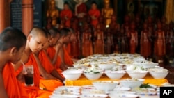 Local Buddhist monks prepare to eat food made by villagers and donated as offerings to the dead during celebrations of Pchum Ben, or Ancestors' Day, at a Buddhist pagoda of Wat Kanty Yaram, in Prek Thoang village, Kandal province, northeast of Phnom Penh, Cambodia Wednesday, Sept. 17, 2014. The traditional 15-day festival, which commemorates the spirits of the dead, began on Sept. 9. (AP Photo/Heng Sinith)