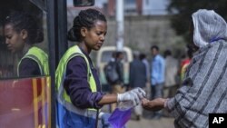 በአዲስ አበባ አንዲት በጎፈቃደኛ የኮረናቫይረስ ስርጭትን ለመከላከል የእጅ ማፅጃ ወደ አውቶብስ ውስጥ ለሚሳፈሩ ሰዎች እየሰጠች © AP Photo/Mulugeta Ayene