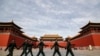 FILE - Soldiers wearing protective face masks march past the closed entrance gates to the Forbidden City, usually crowded with tourists before the coronavirus outbreak in Beijing, March 12, 2020.