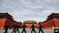 Soldiers wearing protective face masks march past the closed entrance gates to the Forbidden City, usually crowded with tourists before the new coronavirus outbreak in Beijing, March 12, 2020.