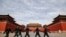 FILE - Soldiers wearing protective face masks march past the closed entrance gates to the Forbidden City, usually crowded with tourists before the coronavirus outbreak in Beijing, March 12, 2020.