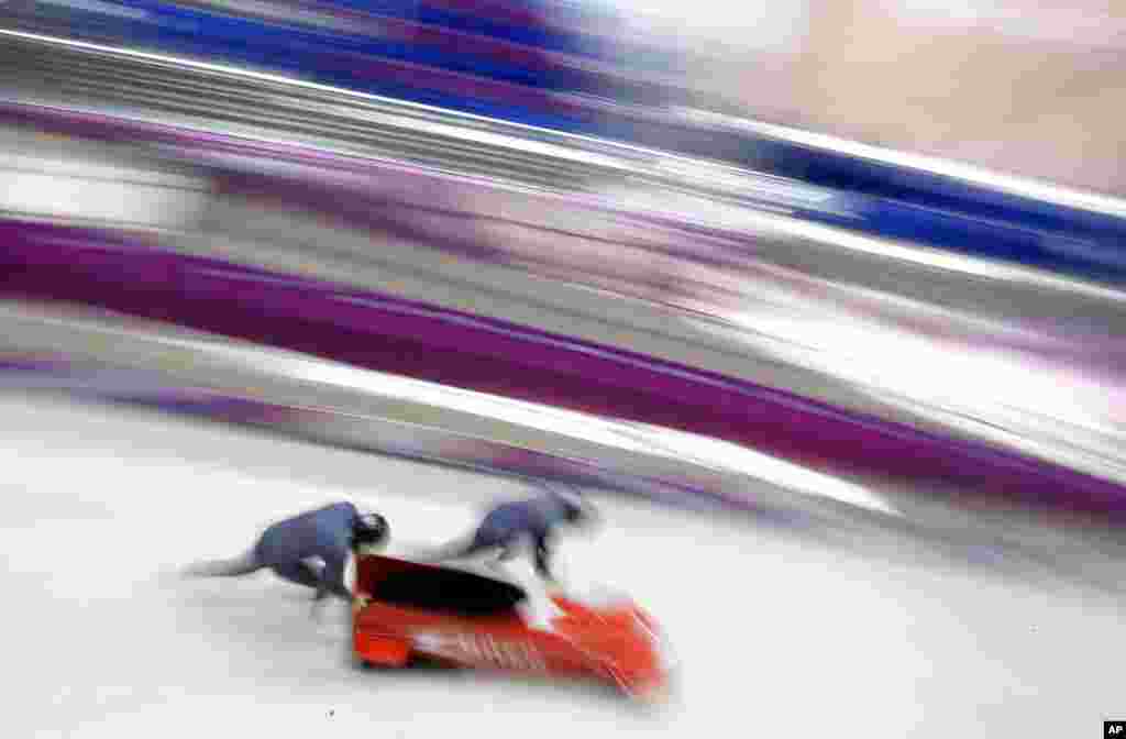 The two-man team from Monaco MON-1, piloted by Patrice Servelle, start a run during a training session for the men's two-man bobsled at the 2014 Winter Olympics, Feb. 14, 2014.