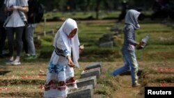 A girl places flowers on the graves of some of the victims who died during the political turmoil of 1998 during a 20th anniversary commemoration at Pondok Ranggon mass grave in Jakarta, Indonesia, May 13, 2018. 