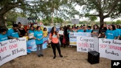 Camila Duarte, center, of Venezuela, speaks in front of the Immigration and Customs Enforcement offices, June 1, 2018, in Miramar, Fla. The demonstration was part on the Families Belong Together Day of Action, where demonstrators in cities across the U.S.