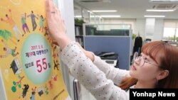 An employee puts up Election Day poster for South Korea presidential election. (Yonhap News)
