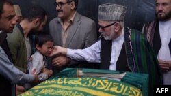 Ten year-old Mustafa, son of Afghan reporter Zabihullah Tamanna,(2L), relatives and friends pray around the coffin during a ceremony at a military hospital in Kabul on June 7, 2016. 