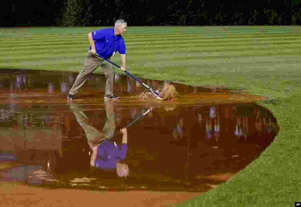 A member of the grounds crew works on the field after a heavy rain soaked Wrigley Field during the fifth inning of a baseball game between the San Francisco Giants and the Chicago Cubs in Chicago, Illinois, USA, Aug. 19, 2014.