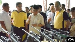Ketua Front Pembebasan Islam Moro (MILF) Murad Ebrahim (tengah) menunjukkan kepada Presiden Filipina Benigno Aquino (kanan) senjata-senjata yang diserahkan sebagai bagian pakta perdamaian, di Sultan Kudarat, provinsi Maguindanao, Filipina, 16 Juni 2015. (VOA/Simone Orendain)