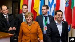 Le Premier ministre grec Alexis Tsipras, à droite, marche avec la chancelière allemande Angela Merkel, au centre, en partant du sommet européen à Bruxelles, le 8 mars 2016. (AP Photo/Virginia Mayo)