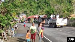 ຮູບນີ້ຖ່າຍໂດຍ UGC ແລະ ໄດ້ຖືກນຳໄປໂພສລົງເຟສບຸກ ໂດຍ ໂຈນາທັນ ກູລລີບານ ໃນວັນທີ 23 ມັງກອນ 2025 ໃຫ້ເຫັນພົນລະເມືອງຢືນໃກ້ກັບຂອບທາງຫຼວງ ທີ່ມີຮອຍແຕກໃນເມືອງ ລີໂລນ, ທາງພາກໃຕ້ຂອງແຂວງ ເລເຕ, ຫຼັງຈາກແຜ່ນດິນໄຫວຄວາມແຮງ 5.8 ກະທົບຕໍ່ແຂວງນີ້.