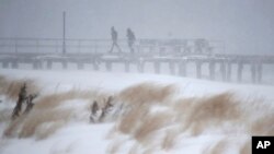 ប្រជាជន​ដើរ​នៅ​លើ​ផ្លូវ​ឆ្នេរ​សមុទ្រ​ដែល​គ្រប​ដណ្តប់​ដោយ​ព្រិល​អំឡុង​ព្យុះ​ព្រិល​ដែល​បាន​បក់​កាត់ ​New Jersey Shore។