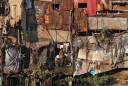 FILE - A man brushes his teeth outside a shanty in Dharavi, one of Asia's largest slums, in Mumbai, India, Dec. 27, 2016.