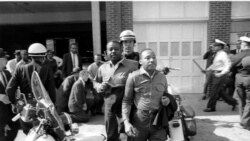 Rev. Ralph Abernathy and Martin Luther King, Jr., are taken by a policeman as they led a line of demonstrators into the business section of Birmingham, Alabama, April 12, 1963.