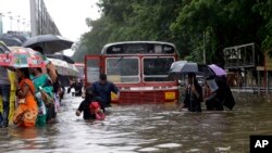 People walk through a waterlogged street following heavy rains in Mumbai, India, Aug. 29, 2017.