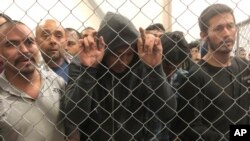 FILE - In this July 12, 2019, photo, men stand in a U.S. Immigration and Border Enforcement detention center in McAllen, Texas.