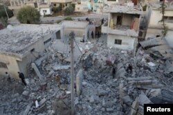 FILE - Residents inspect a damaged site from what activists said were airstrikes carried out by the Russian air force in Nawa city, Deraa, Syria, Nov. 21, 2015.