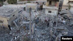 Người dân kiểm tra hiện trường bị tàn phá từ cuộc không kích được thực hiện bởi các lực lượng không quân Nga tại thành phố Nawa, Deraa, Syria, ngày 21/11/2015.