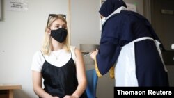 Seorang perempuan menerima suntikan vaksin COVID-19 di rumah sakit Central Middlesex di London, Inggris (foto: dok). 