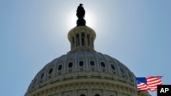 FILE - The US flag flies next to the Capitol in Washington, as Congress and the Obama Administration continue work to raise the debt ceiling.